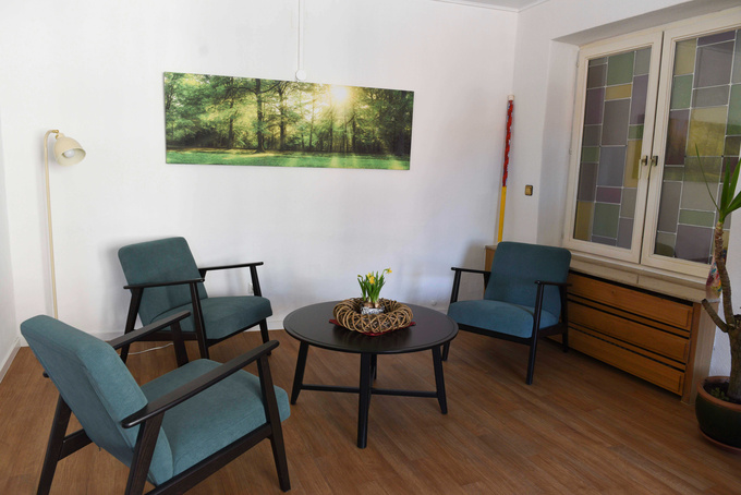 Eine Sitzgruppe, bestehend aus drei Sesseln und einem kleinen Tisch, vermittelt Wohnzimmeratmosphäre.