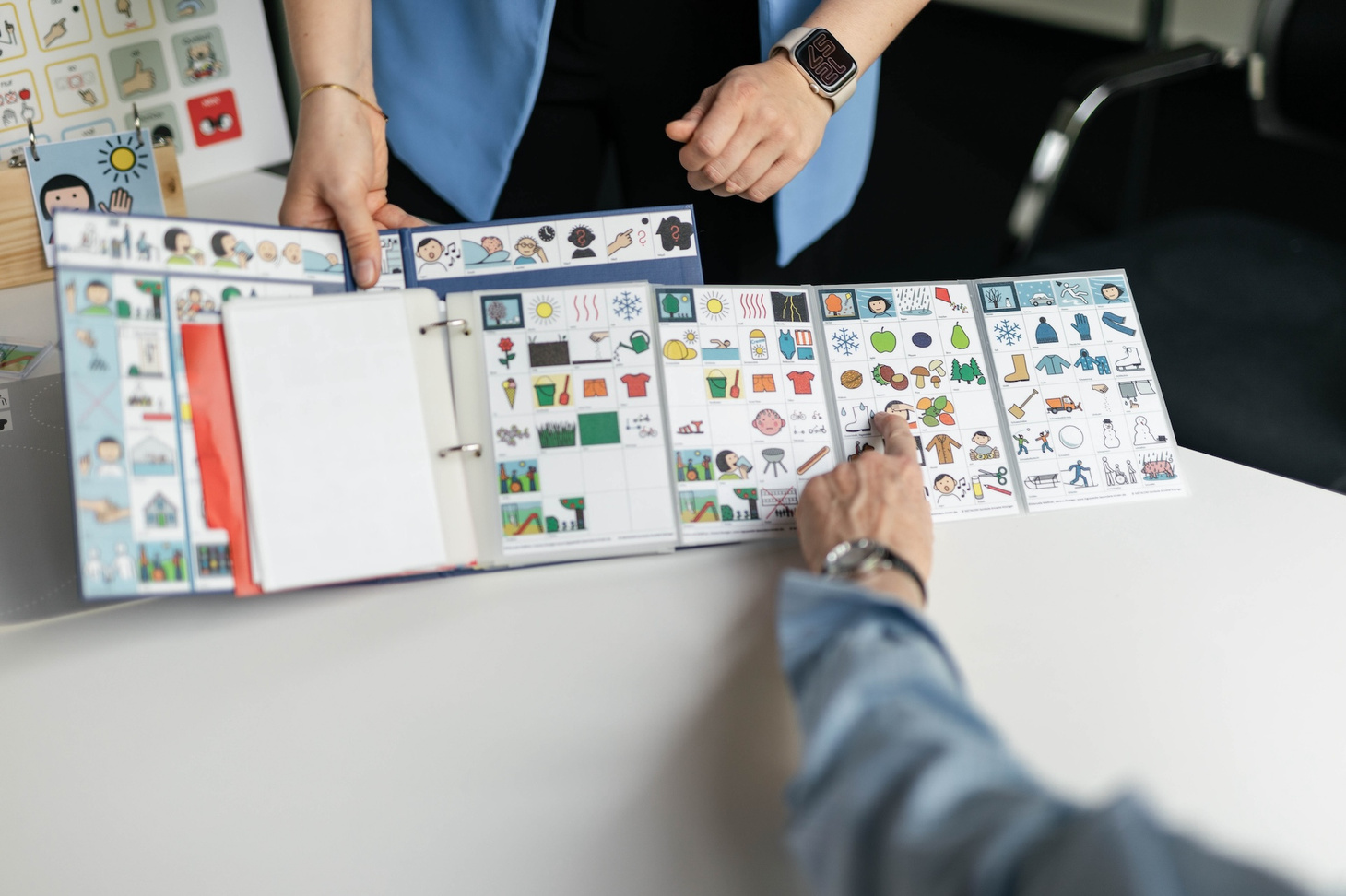 Ein Buch mit einem Symbolüberblick zum Ausklappen. Eine Person zeigt auf ein Symbol.