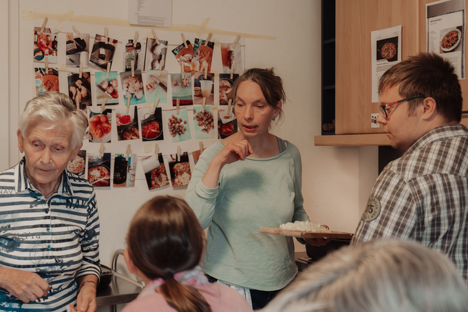 Personen stehen in der Küche und unterhalten sich.