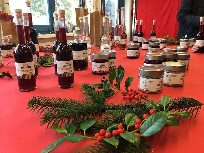 Weihnachtlich dekorierter Verkaufstisch mit Geschenkideen aus der Werkstattküche, z.B. Marmeladen, Aufstrichen, Likören und Keksen.