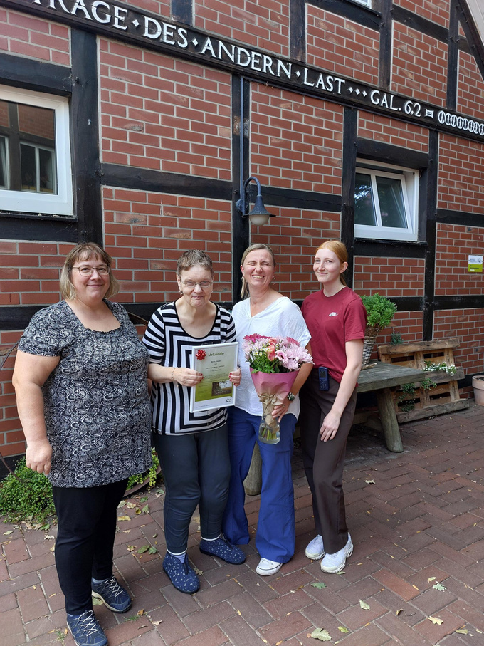 Marion Bremert (2.v.l.) posiert mit Wegbegleitern für ein Gruppenfoto zu ihrem 40. Jubiläum als Bewohnerin von Haus Quadenort. 