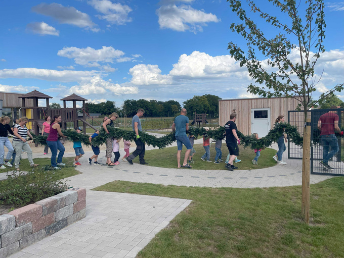Eltern und Kinder tragen gemeinsam den bunten Türkranz.