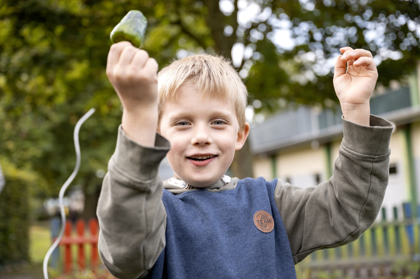 Ein Kind mit frischer Paprika in der Hand im Gemüsegarten.
