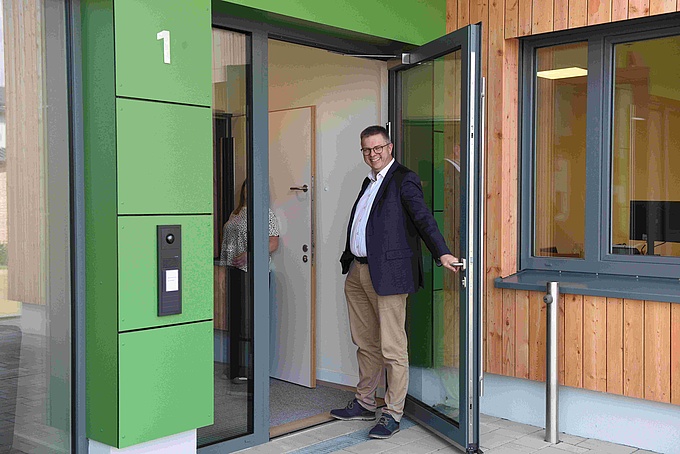 Samtgemeindebürgermeister Michael Wernke öffnet gut gelaunt die Tür zum neuen  Kinderzentrum Kunkheide.  