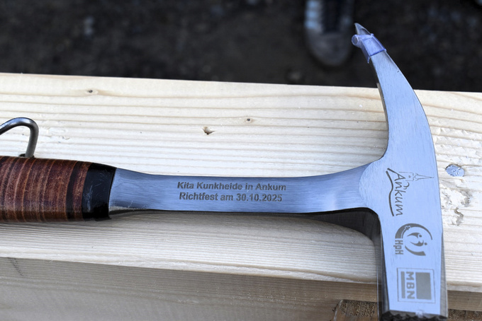 Auf einem Hammer sind folgende Angaben eingraviert: Datum, Anlass und die Logos von Gemeinde, Träger und Bauunternehmen.