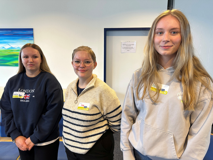 Drei junge Personen lächeln in die Kamera.