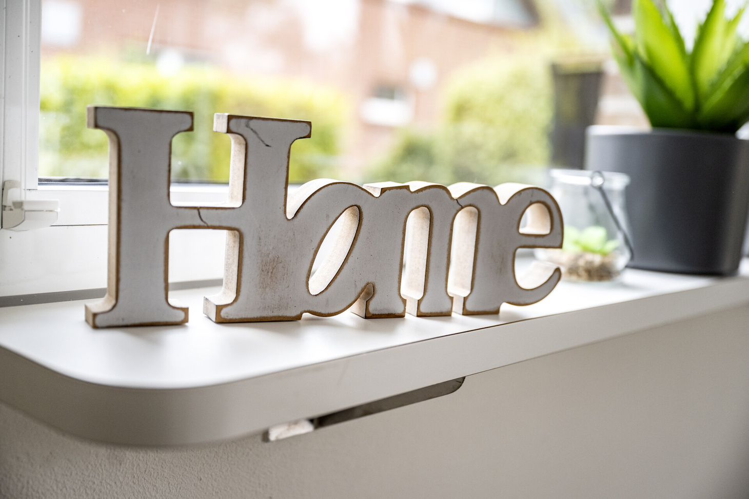 Auf einer Fensterbank steht auch Holzbuchstaben das Wort "Home"