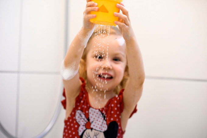 Ein Kind im Badeanzug spielt mit Wasser.