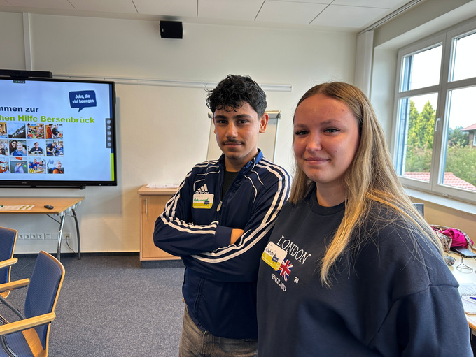 Zwei junge Personen lächeln in die Kamera.