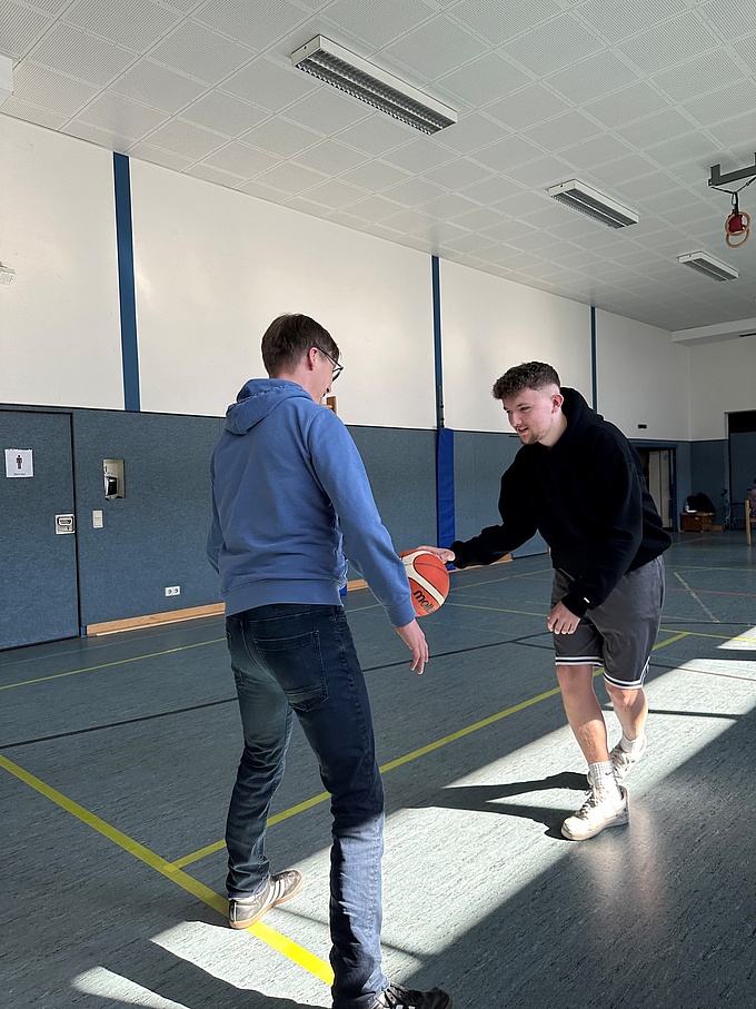 Ein Spieler steht defensiv vor Reik, der einen Basketball dribbelt.