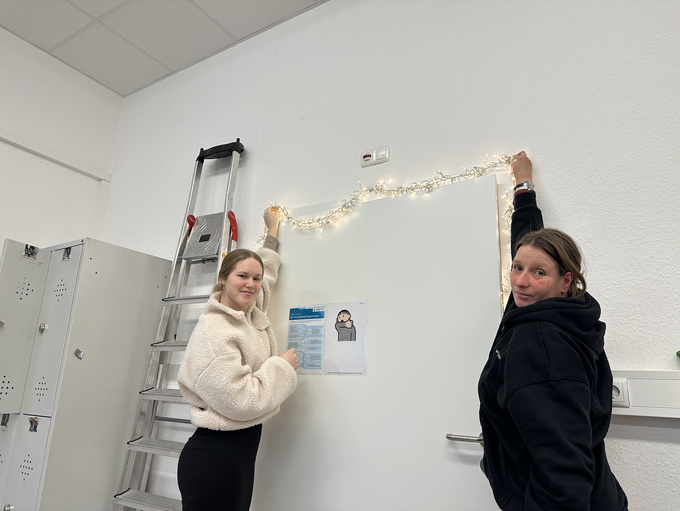 Josefina und Andrea hängen im Bramscher Bahnhof eine Lichterkette auf.