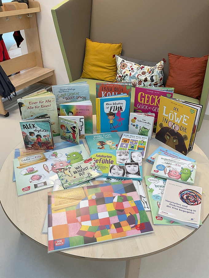 Eine Auswahl altersgerechter Kinderbücher rund um Emotionen liegt auf einem Tisch.