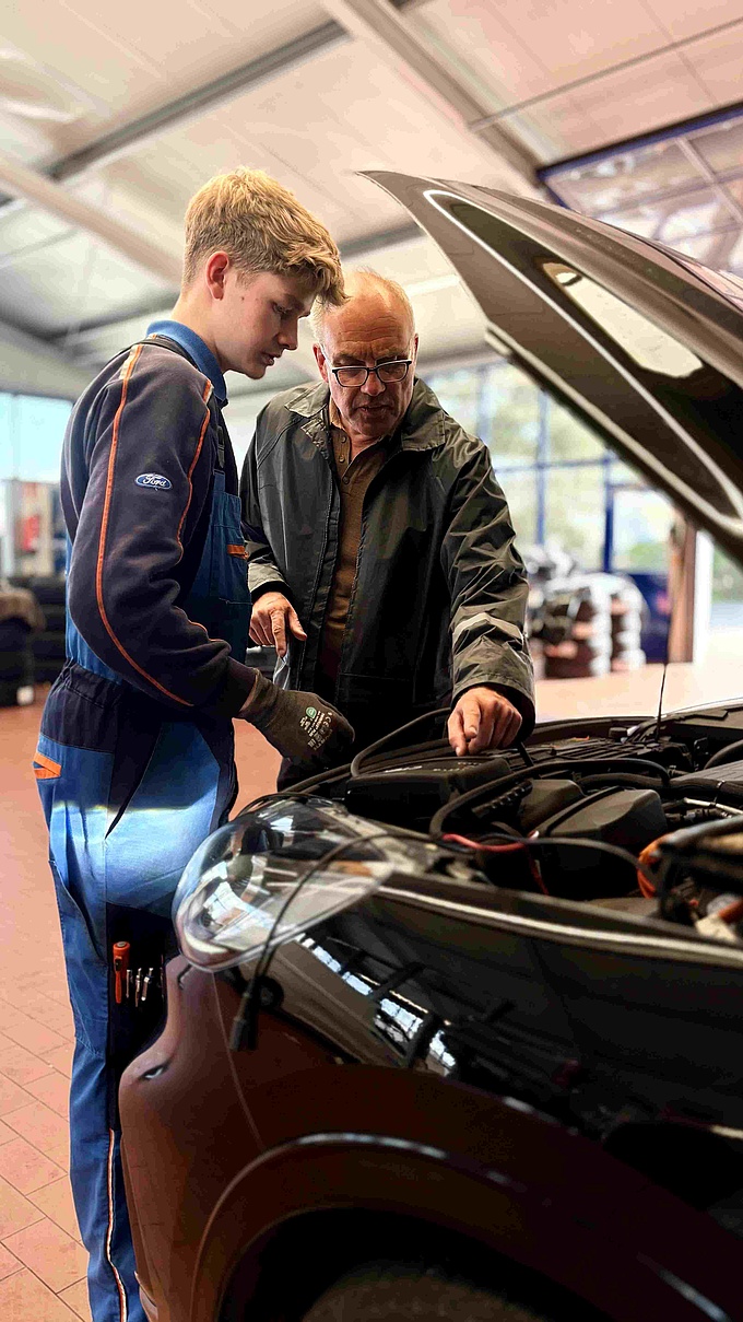 Timon Eichhorn, Auszubildender im Autohaus Wernsing, zeigt Thomas Hilgen, wie er den Motor eines Wagens kontrolliert. 