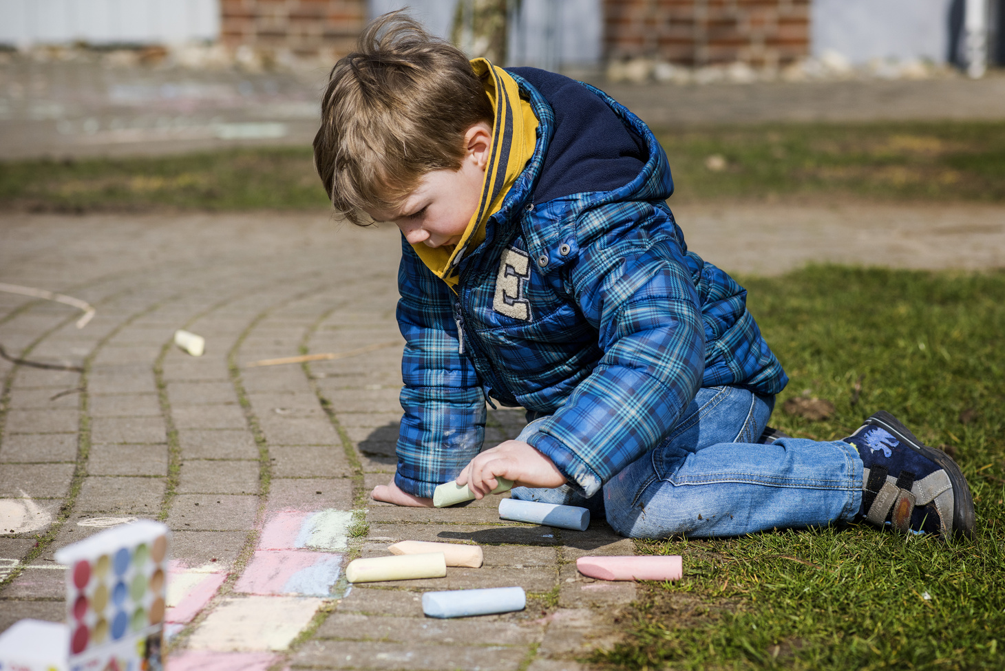 Kind malt mit Kreide auf einem Steinboden