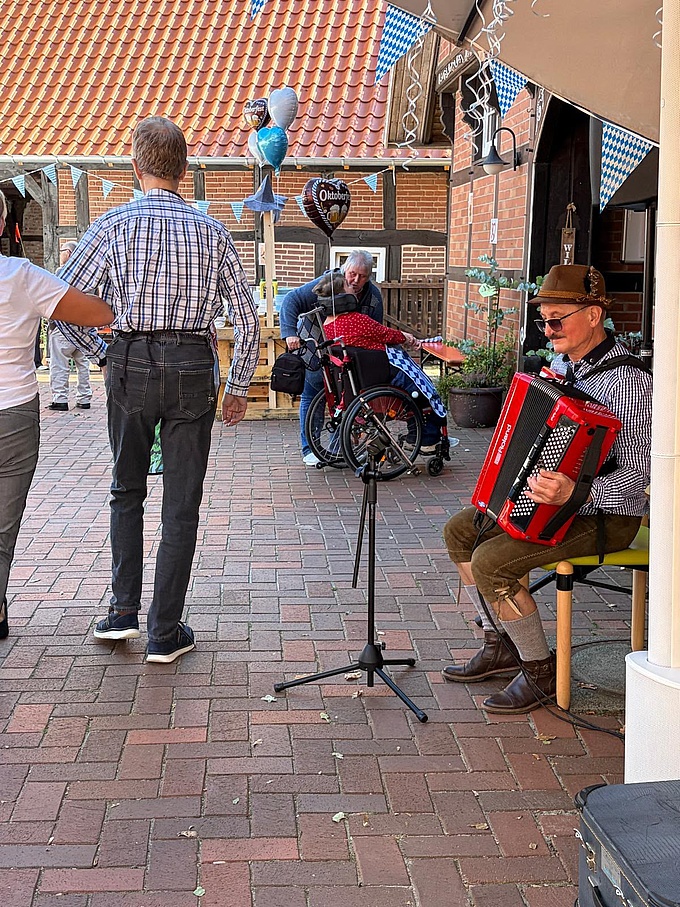 Ein Musiker spielt auf dem Akkordeon. Zwei Bewohnende gehen auf die Tanzfläche.