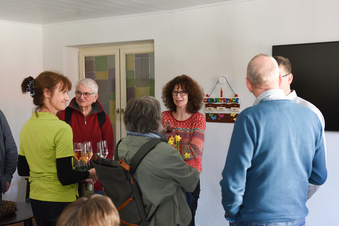 Mehrere Gäste unterhalten sich bei einem Glas Sekt oder O-Saft.