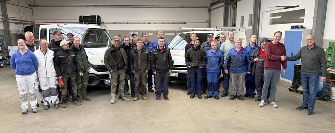 Gruppenfoto: Die Mitarbeitenden aller vier BeTec-Bereich sowie EInrichtungsleitung Matthias Herrmann und Bereichsleiter Martin Heimbrock. Herrmann und Heimbrock reichen sich die Hände.