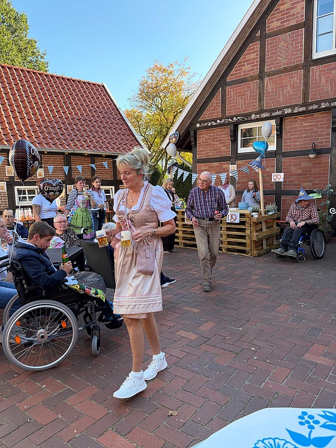 Eine Frau im Dirndl trägt zwei kleine Krüge Bier.