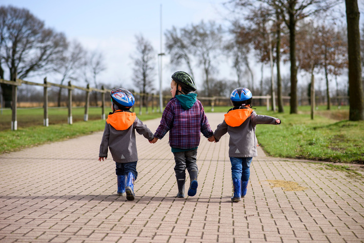 Drei Kinder halten sich an den Händen und spazieren zum Reitsportzentrum