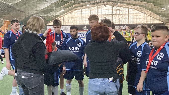 Zwei Frauen hängen den Spielern Medaillen um den Hals.
