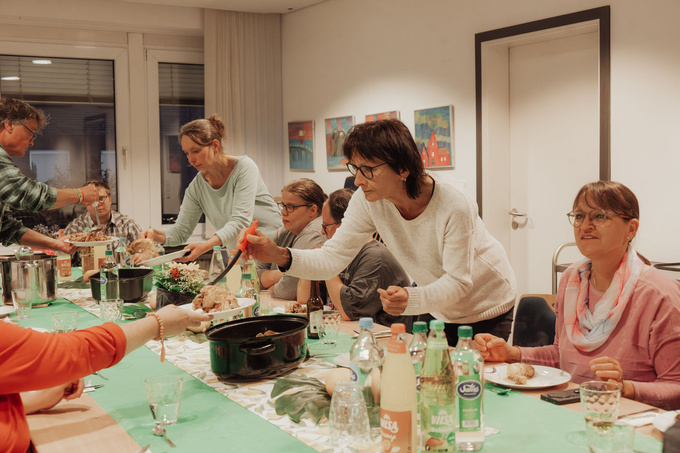 Mehrere Personen sitzen am Tisch und essen.