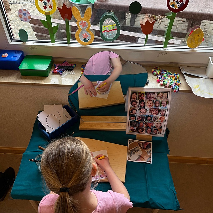 Ein Mädchen betrachtet sich selbst im Spiegel und malt sich auf einem Blatt Papier.len