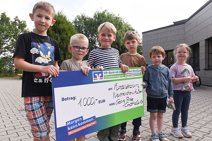 Einige Kinder aus dem Kinderzentrum im Hülsen halten den symbolischen Scheck in den Händen. Foto: Elisabeth Schomaker.