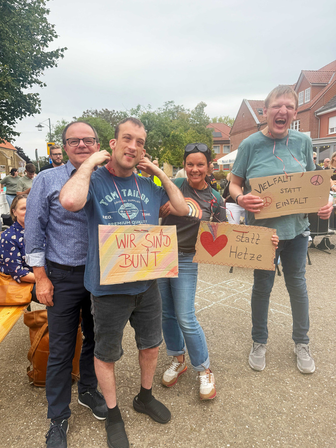 Geschäfsführer Guido Uhl, zwei Bewohner und eine Mitarbeiterin bei der Demonstration. Sie tragen Schilder mit folgenden Aufschriften: "Wir sind bunt", "Herz statt Hetze" und "Vielfalt statt Einfalt". 